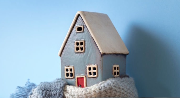 House model wrapped in scarf on radiator home winter heating and insulation background fuel and energy crisis concept